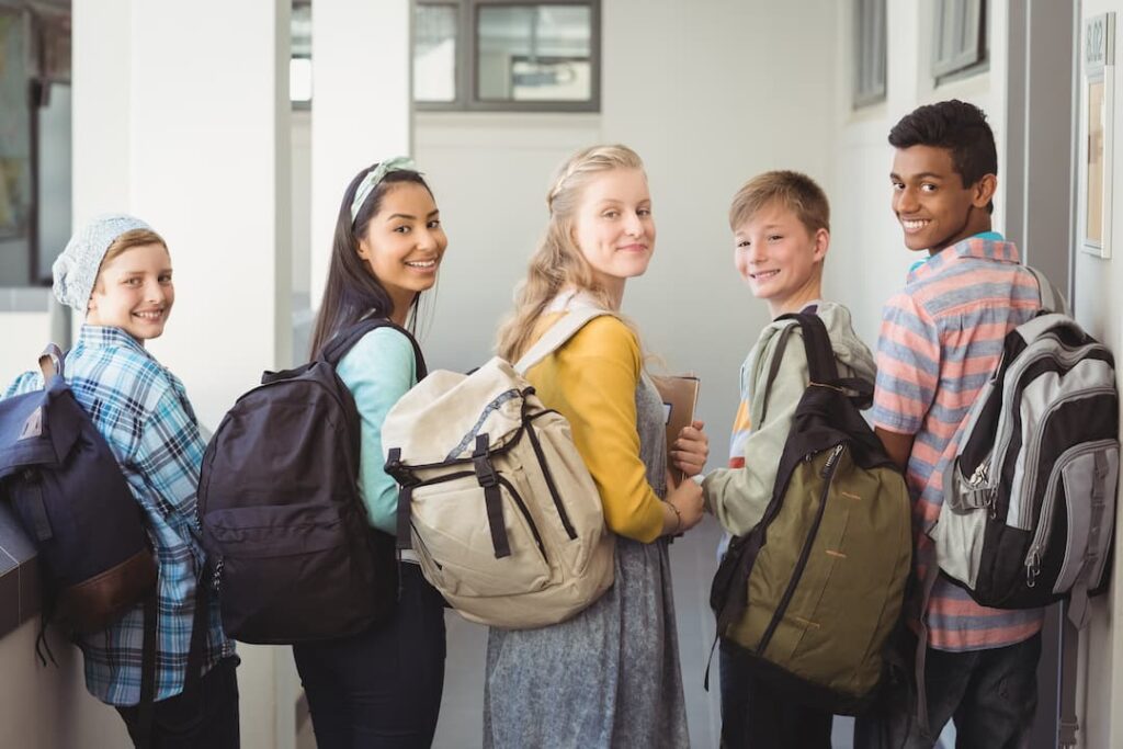Retrato de estudiantes sonrientes de pie con cuaderno y mochila - vuelta al cole Retrato de estudiantes sonrientes de pie con cuaderno y mochila - vuelta al cole